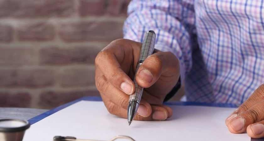 man writing on clipboard